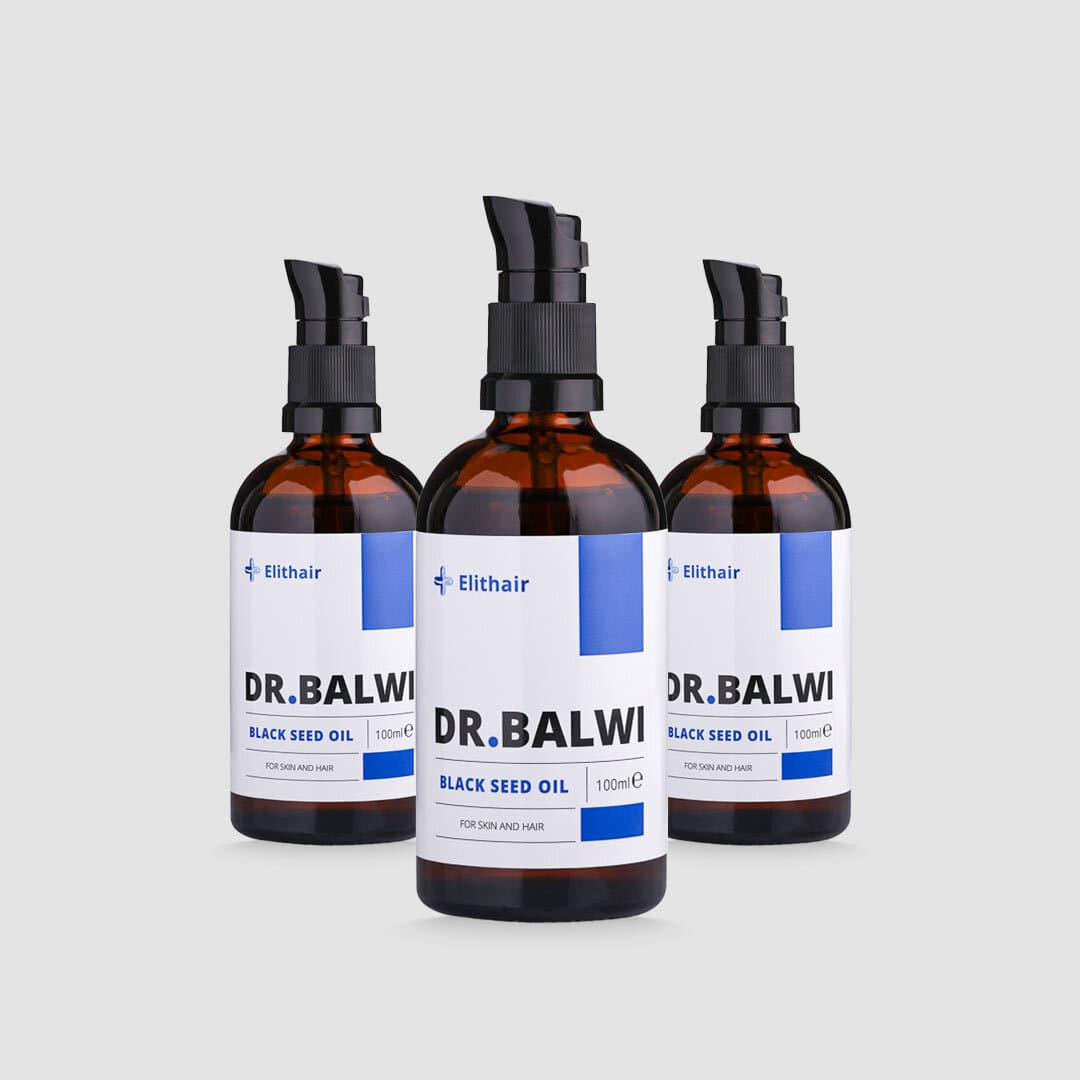 Auf hellgrauem Hintergrund sind drei bernsteinfarbene Flaschen shop.elithairtransplant Premium Schwarzkümmelöl mit schwarzen Pumps und blau-weißen Etiketten zu sehen – perfekt für Haarpflege und Vorbeugung von Haarausfall.