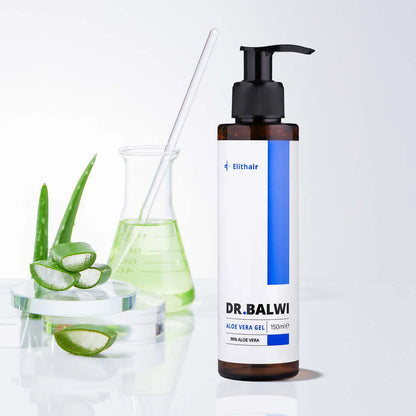 Eine Flasche Dr. Balwi 98 % Aloe Vera von shop.elithairtransplant steht zusammen mit Aloe-Blättern, einem Becher mit grüner Flüssigkeit und einer durchsichtigen Schale – ideal für Feuchtigkeit und Pflege der Kopfhaut – auf einer weißen Oberfläche vor einem hellen Hintergrund.