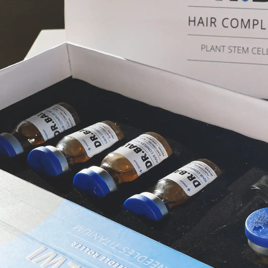 Vier kleine Fläschchen mit blauen Kappen mit der Aufschrift Dr. Balwi Meso Therapie (Refill) aus dem Dr. Balwi Shop sind in einem schwarzen Schaumstoffeinsatz in einer offenen Schachtel angeordnet, die mit Haarwachstum und Schutz vor Haarausfall wirbt. Auf dem Deckel stehen HAIR COMPLEX und PLANT STEM CELLS.
