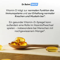 Ein Holzlöffel mit gelben Vitamin D 1000 IE Kapseln von Dr. Balwi Shop liegt auf heller Fläche, daneben weitere Kapseln. Im Hintergrund Hinweise zu Vorteilen von Vitamin D und seinem Zusammenhang mit Haarausfall.