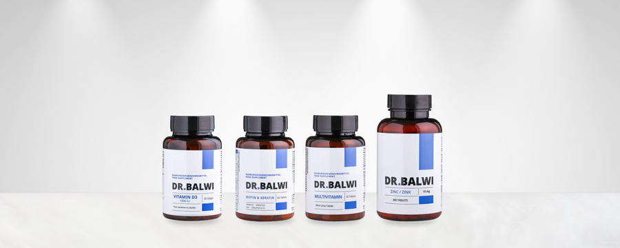 Vier braune Nahrungsergänzungsflaschen mit der Aufschrift DR.BALWI sind in einer Reihe auf einer weißen Fläche mit einem hellgrauen Hintergrund und dezenten Scheinwerfern über dem Kopf angeordnet. Jede Flasche zeigt unterschiedliche Produktnamen und Details.